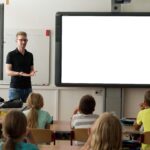 Lehrer steht im Klassenzimmer vor Schülern