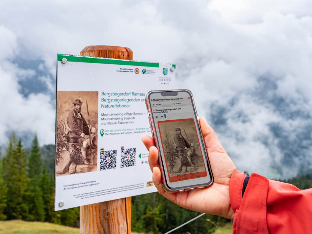 Besucher hält die App zur Biosphären-Drehscheibe am Hirschkaser vor ein entsprechendes Informationsschild