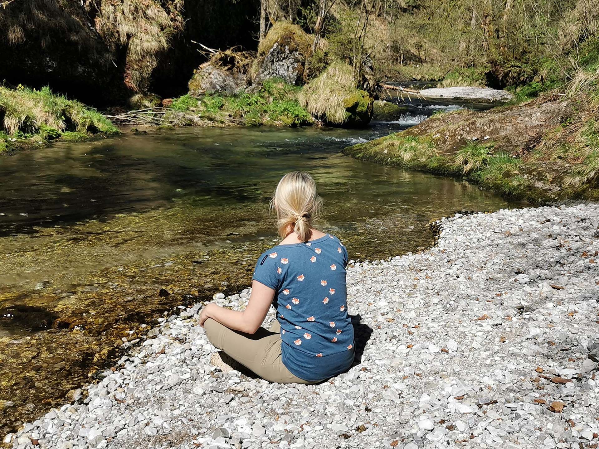 Frau meditiert am Bachbett