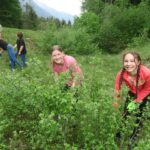 Schülerinnen einer Partnerschule helfen auf der Alm beim Schwenden