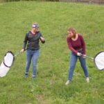 Forschende fangen mit einem Kescher auf der Wiese Insekten