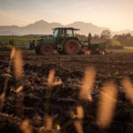 Traktor pflügt vor Bergkulisse einen Acker