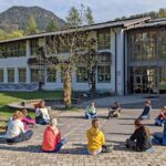 Sitzkreis von Kindern vor der Grundschule Ramsau im Rahmen einer Bildungsveranstaltung