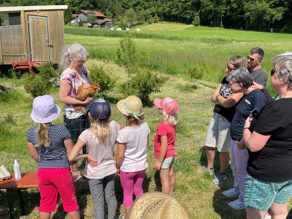 Teilnehmer der Bauernhofexkursion bei der Erkundung des Hühnergeheges