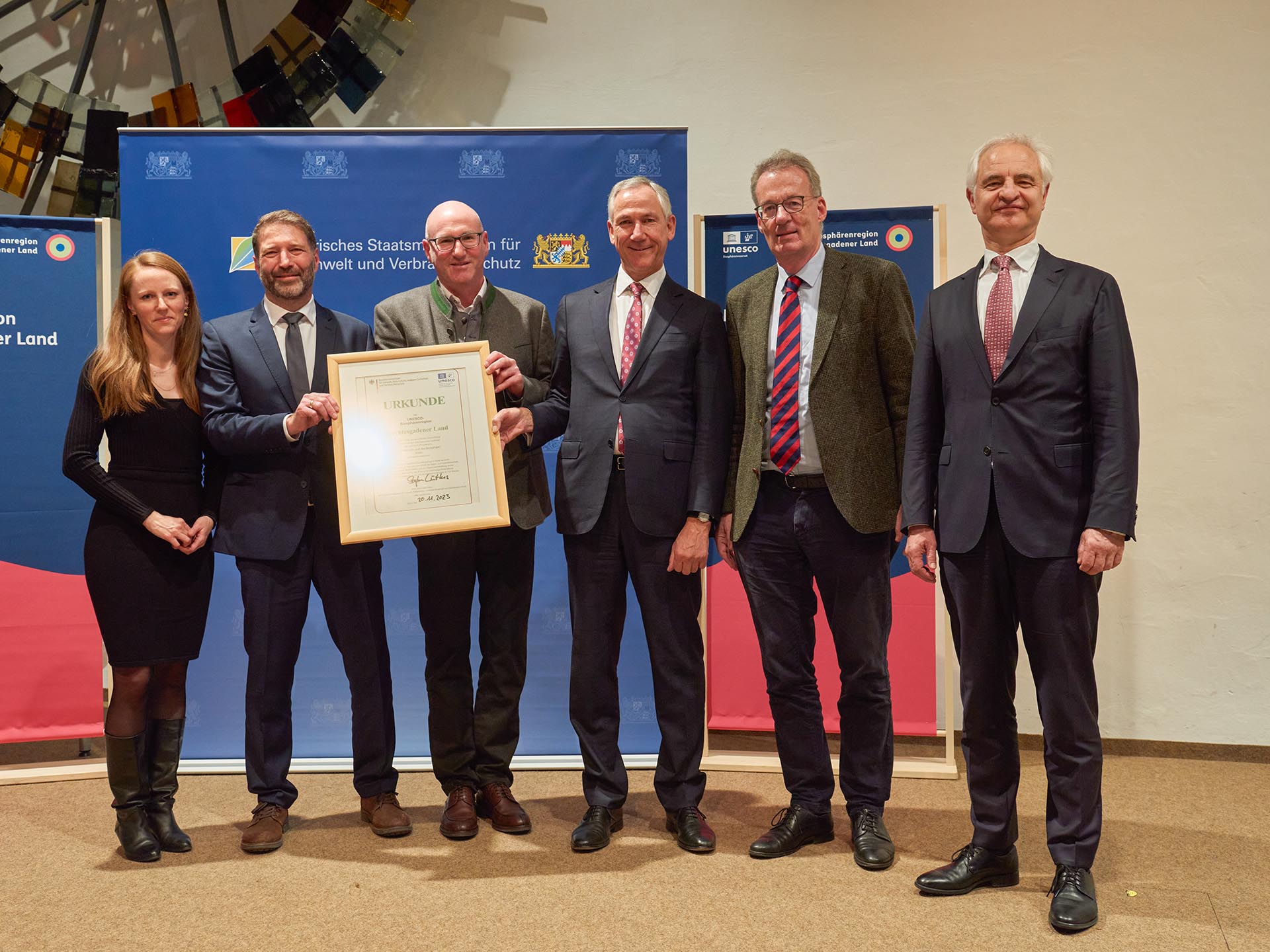 Gruppenfoto nach der Urkunden-Übergabe mit Bernadette Kneis (Stellvertretende Leiterin der Biosphären-Verwaltung), Dr. Peter Loreth (Leiter der Biosphären-Verwaltung), Bernhard Kern (Landrat Berchtesgadener Land), Dr. Christian Barth (Amtschef des Bayerischen Staatsministeriums für Umwelt und Verbraucherschutz), Dr. Stefan Lütkes (Vorsitzender des MAB-Nationalkomitees), Dr. Konrad Schober (Regierungspräsident von Oberbayern)