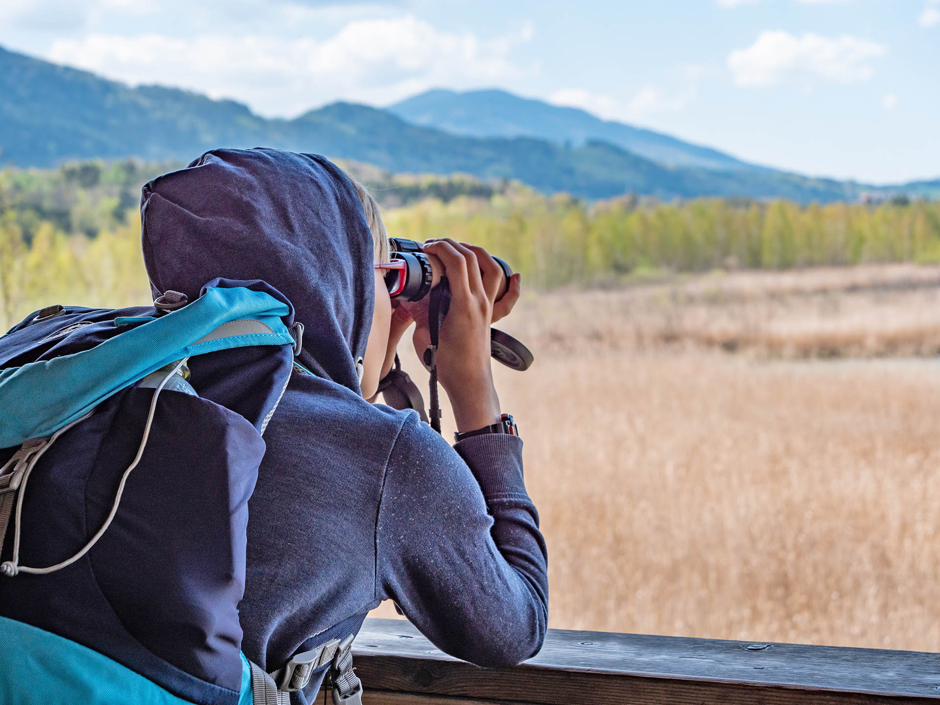 Junge mit Fernglas auf einem Aussichtsturm im Ainringer Moos
