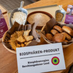 Zertifizierte Biosphären-Produkte Bergsteigerglück und Hoamat Weckerl in Körbchen präsentiert auf einem Tisch mit Biosphären-Produkt-Schild