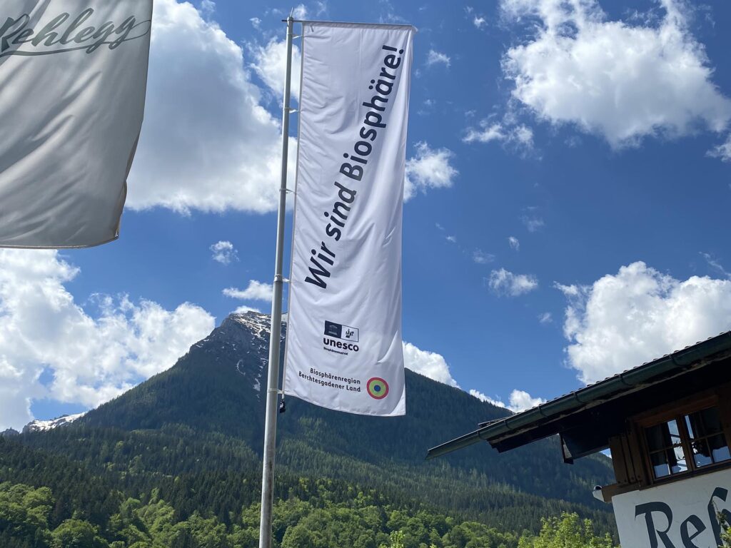 Fahne mit Schriftzug "Wir sind Biosphäre!" vor Bergkulisse