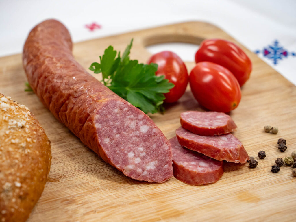 Brotzeitbrett mit aufgeschnittener Biosphären-Kabanossi, Semmel und Tomaten